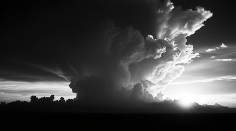 A captivating black and white cinematic photograph depicts a dramatic thunderstorm cloudscape illuminated by the vibrant hues