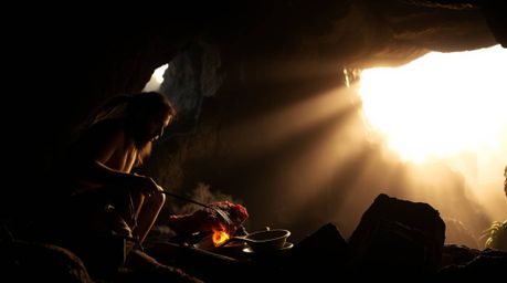 Experience a dreamy atmosphere brought to life with contrasting chiaroscuro lighting, depicting a caveman engrossed in cookin