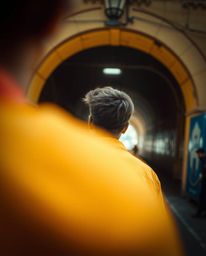 A vibrant and energetic candid street photograph capturing a person standing at the edge of a tunnel, gazing towards the ligh