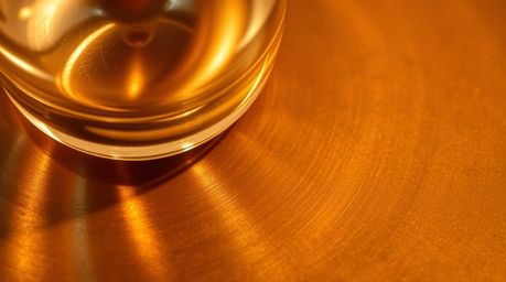 This captivating image showcases a close-up detail of a glass object reflecting smooth gradient textures onto a cast bronze s