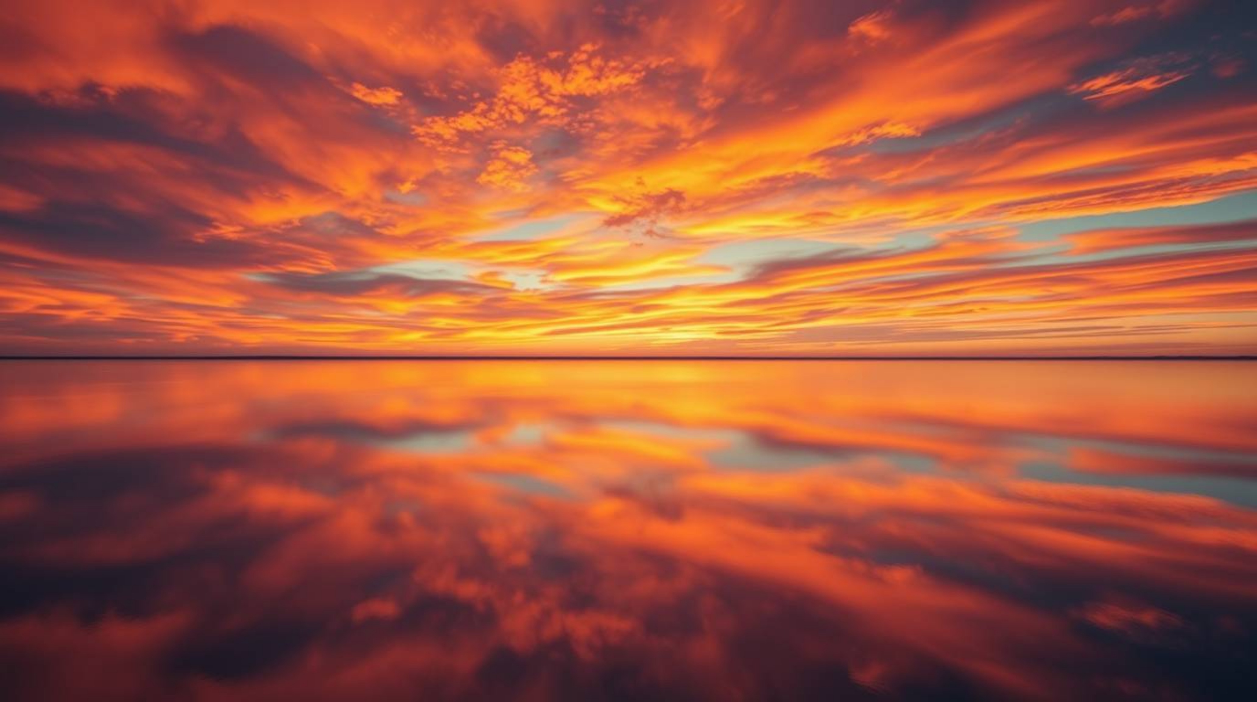 An overhead shot captures a tranquil lake mirroring a breathtaking sunset.  The vibrant complementary colors create a dreamli