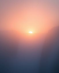 An ethereal, spiritual vibe photograph of a sun setting behind a dramatic waterfall. Thick fog creates a low visibility atmos