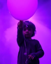 A captivating image of a child holding a balloon bathed in deep ultraviolet light. Vivid purples and high contrast create a s