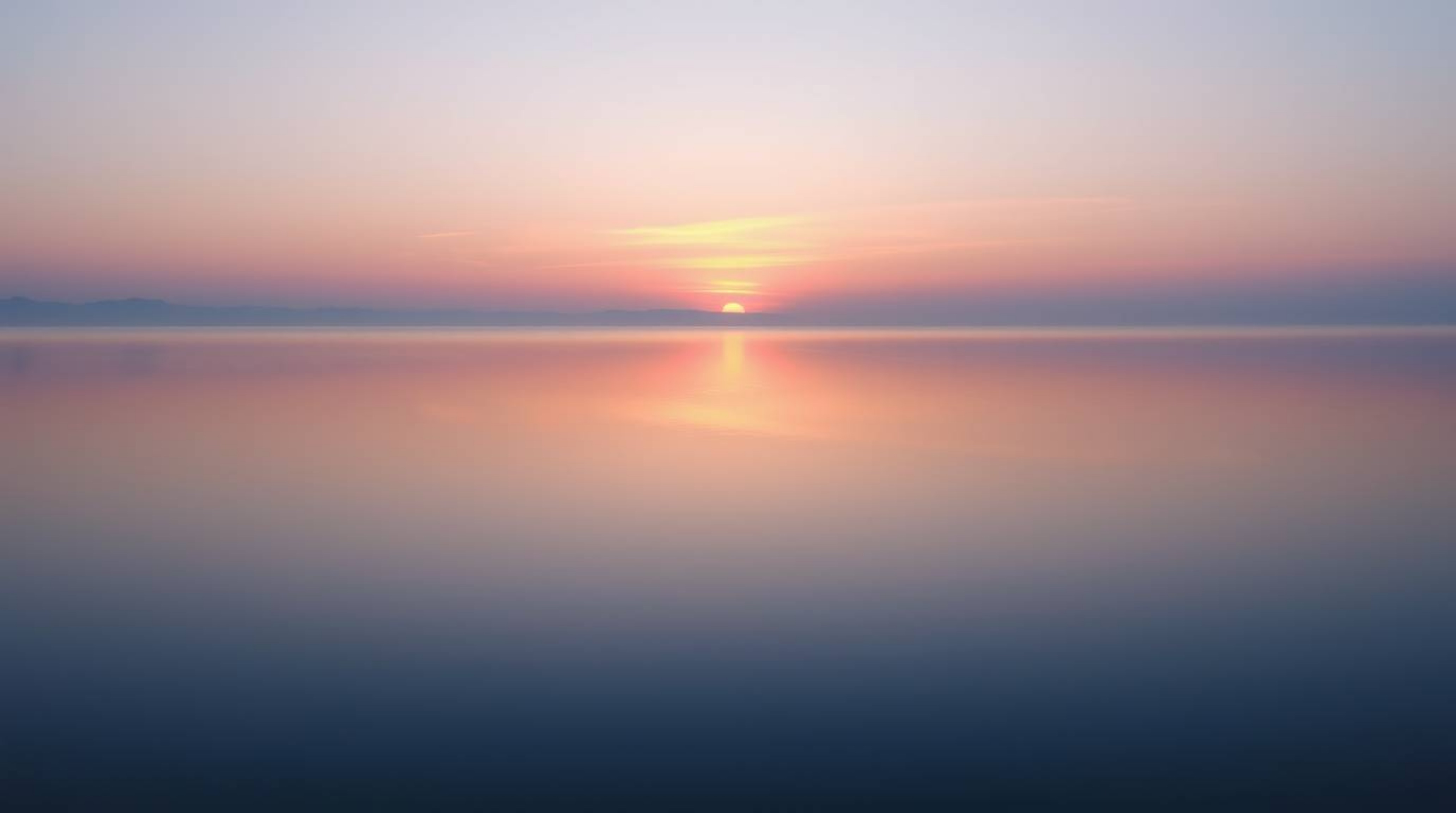 A captivating image showcasing a lake serenely reflecting the vibrant hues of a pastel or vivid sunset sky. The scene evokes 