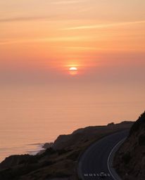 This artwork depicts a sunset sky over a winding coastal highway, rendered in a palette of natural earth tones. The scene is 