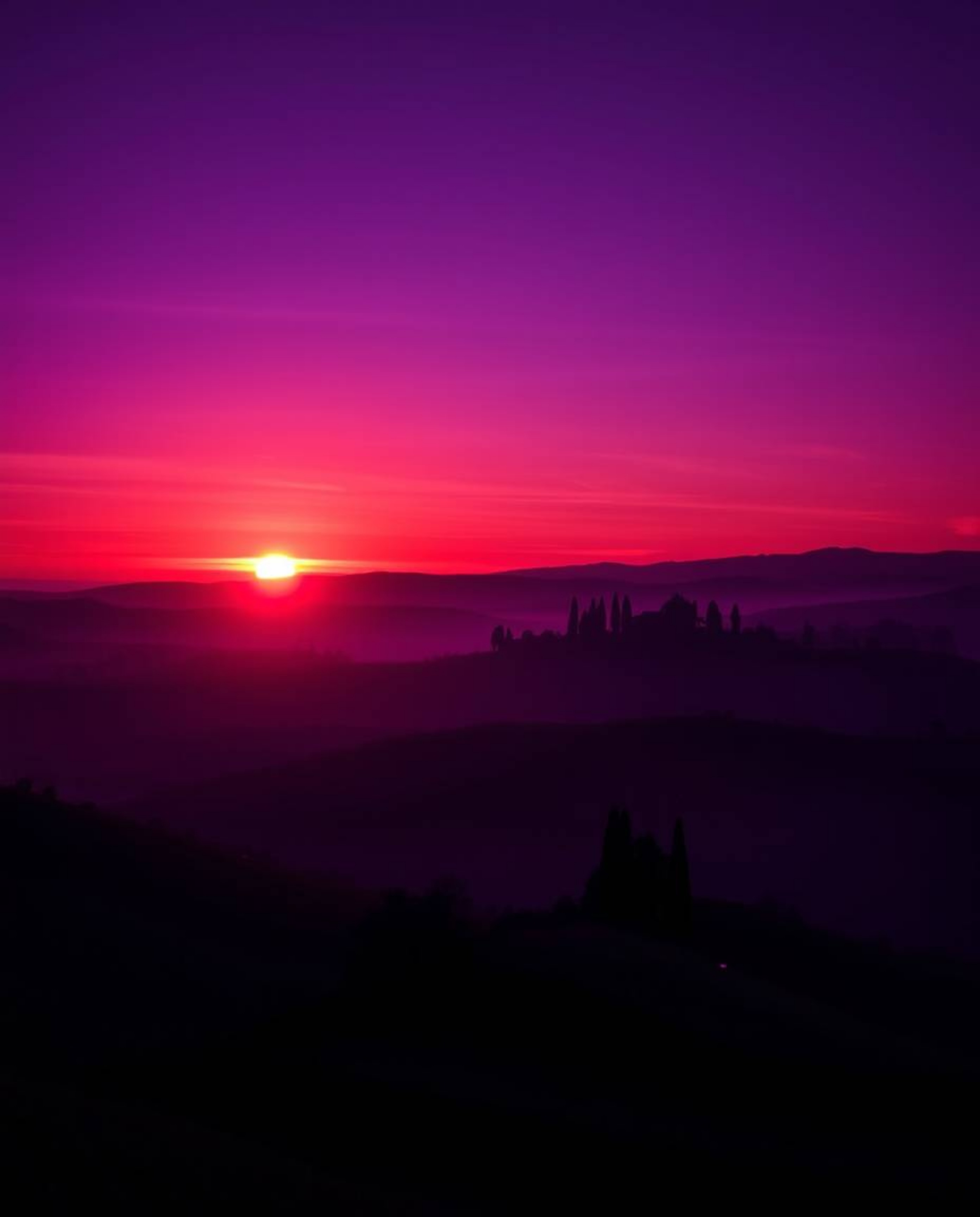Deep ultraviolet hues paint a vivid high contrast sunset over misty Tuscan hills, emphasizing the intense purples and dark sh