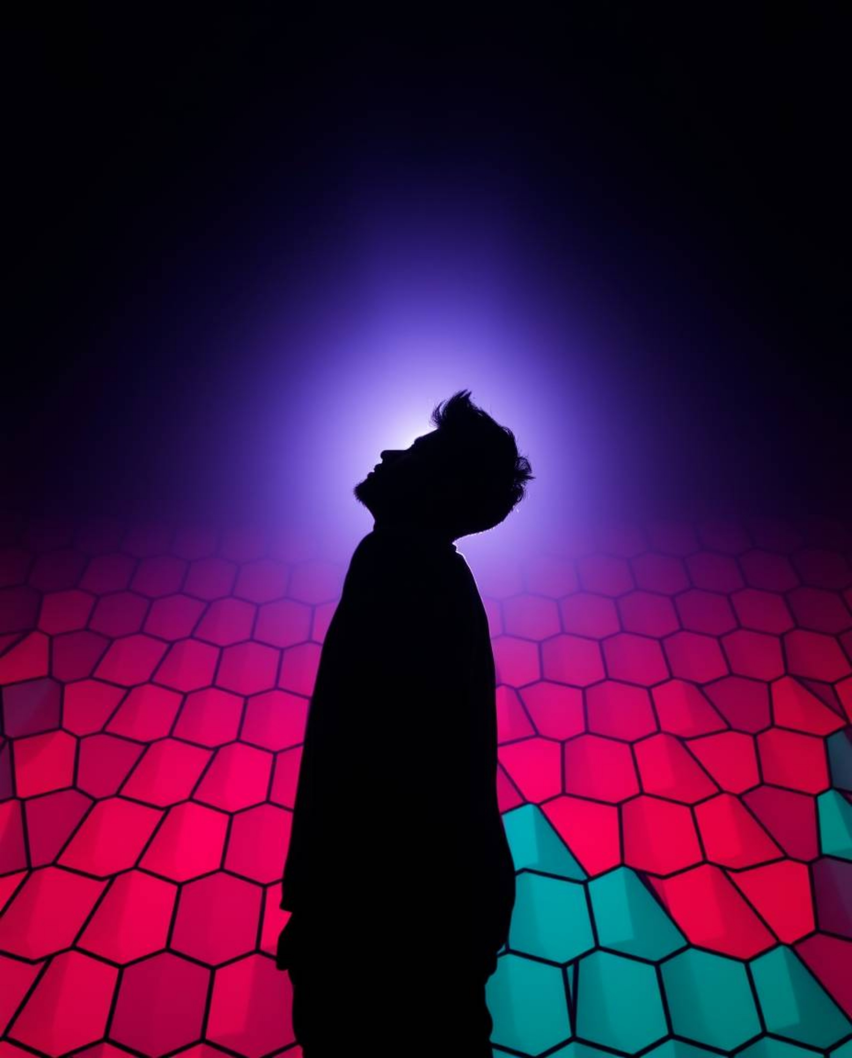 Explore a visually striking low-angle perspective featuring a silhouetted figure, backlit by a vibrant light source. This ima