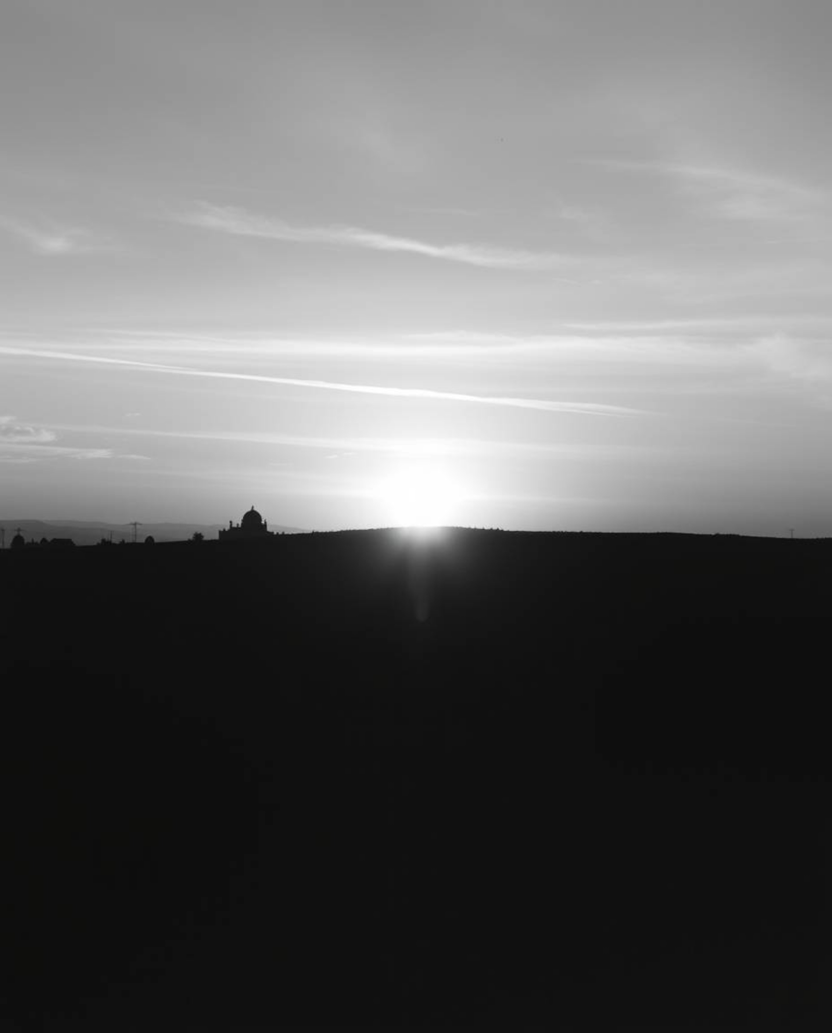 A classic black and white photograph capturing the serene beauty of a sunrise over a war-torn landscape. The image conveys gr