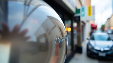 A captivating candid street photograph showcases a detailed close-up of a glass object reflecting smooth gradient textures.  