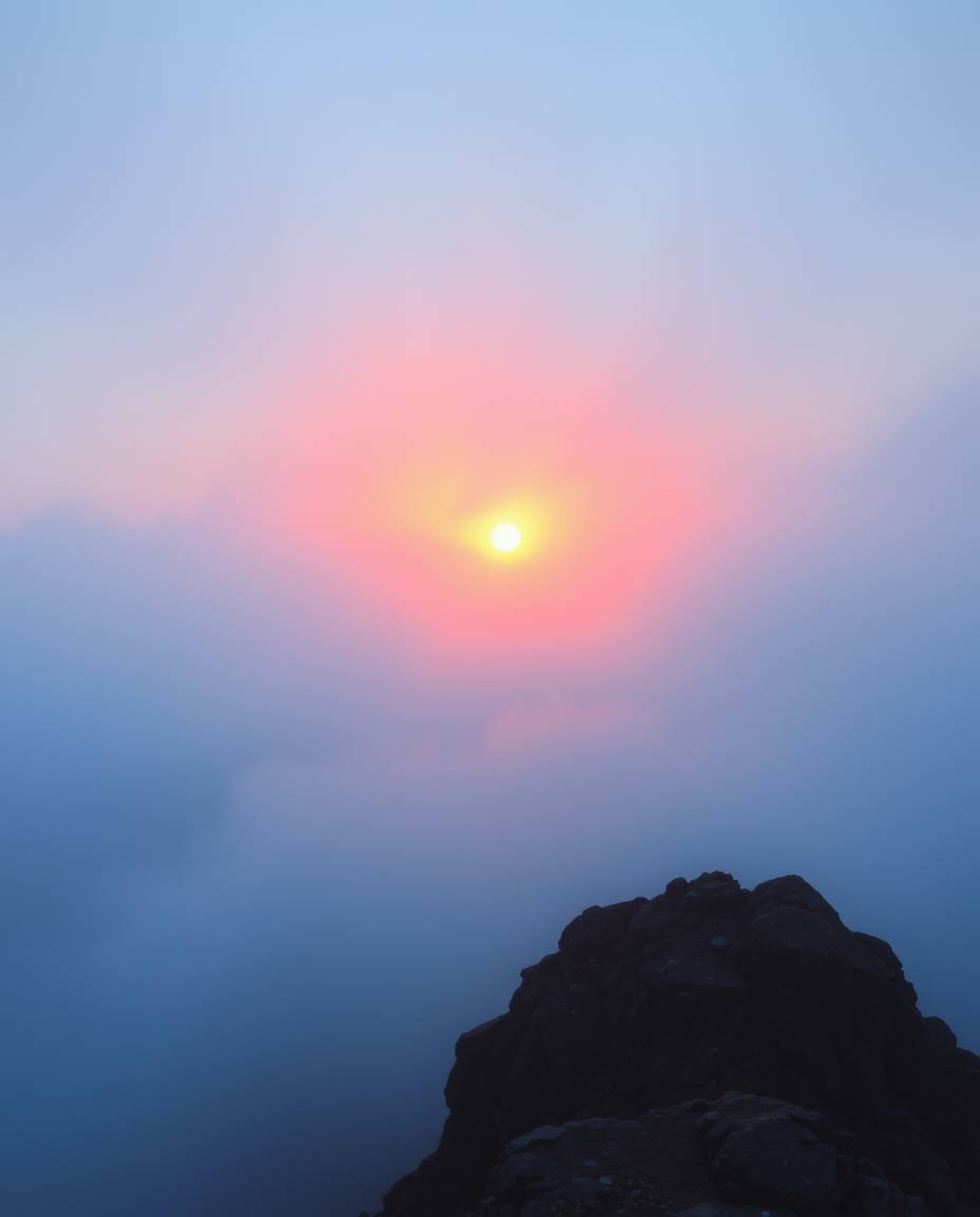 This painting exudes an ethereal and spiritual vibe, capturing a sunset from a high alpine peak enveloped in thick, foggy sur