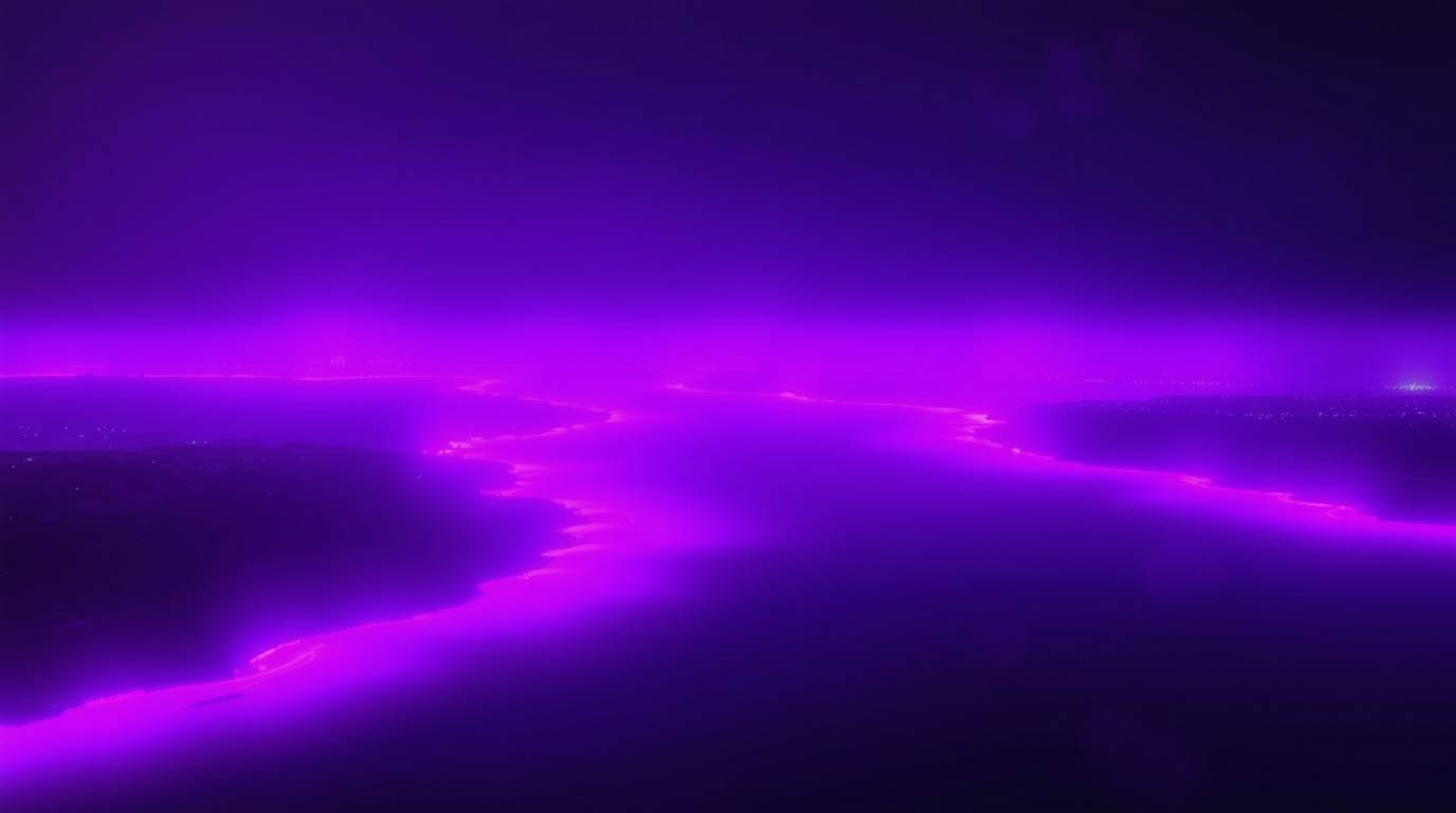 Experience a breathtaking cinematic portrayal of a river delta bathed in deep ultraviolet hues, presented with a soft haze th