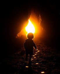 A captivating image featuring a child silhouette against warm, golden backlighting, following a trail of glowing footsteps le