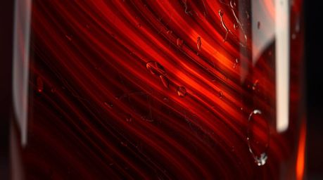 This image features a captivating close-up detail of a glass object, reflecting smooth gradient textures under intense and dr