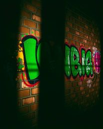 Experience the unsettling beauty of graffiti art. This image showcases vibrant, colorful splashes of paint on a rough brick w