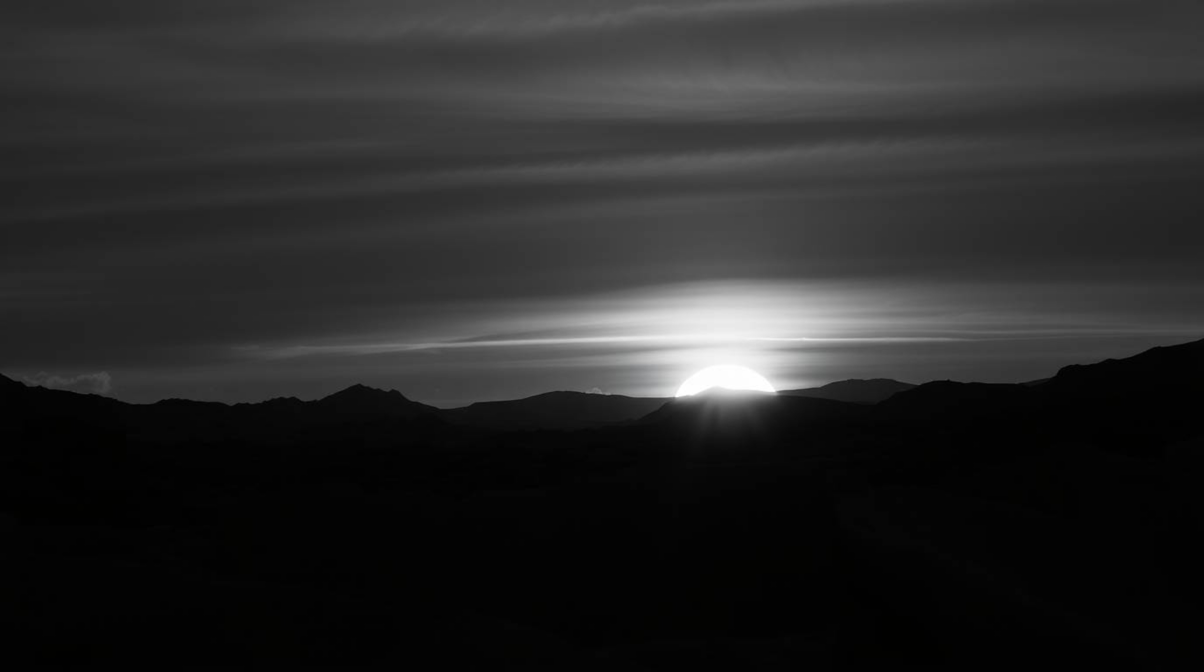 A classic black and white photograph captures an eerie sunset over icy polar glaciers, utilizing dark tones to create an unse