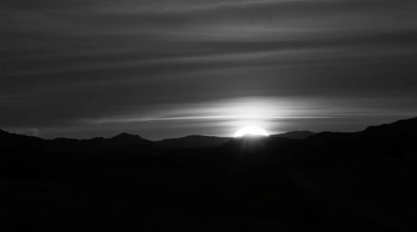 A classic black and white photograph captures an eerie sunset over icy polar glaciers, utilizing dark tones to create an unse