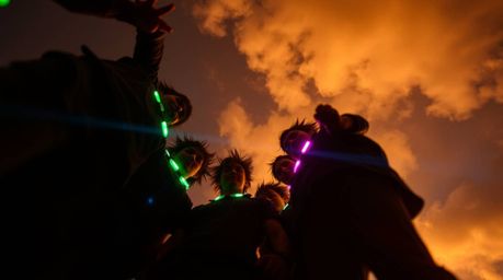 Discover a captivating image of misfit heroes banding together, their faces turned upwards, illuminated by vibrant biolumines