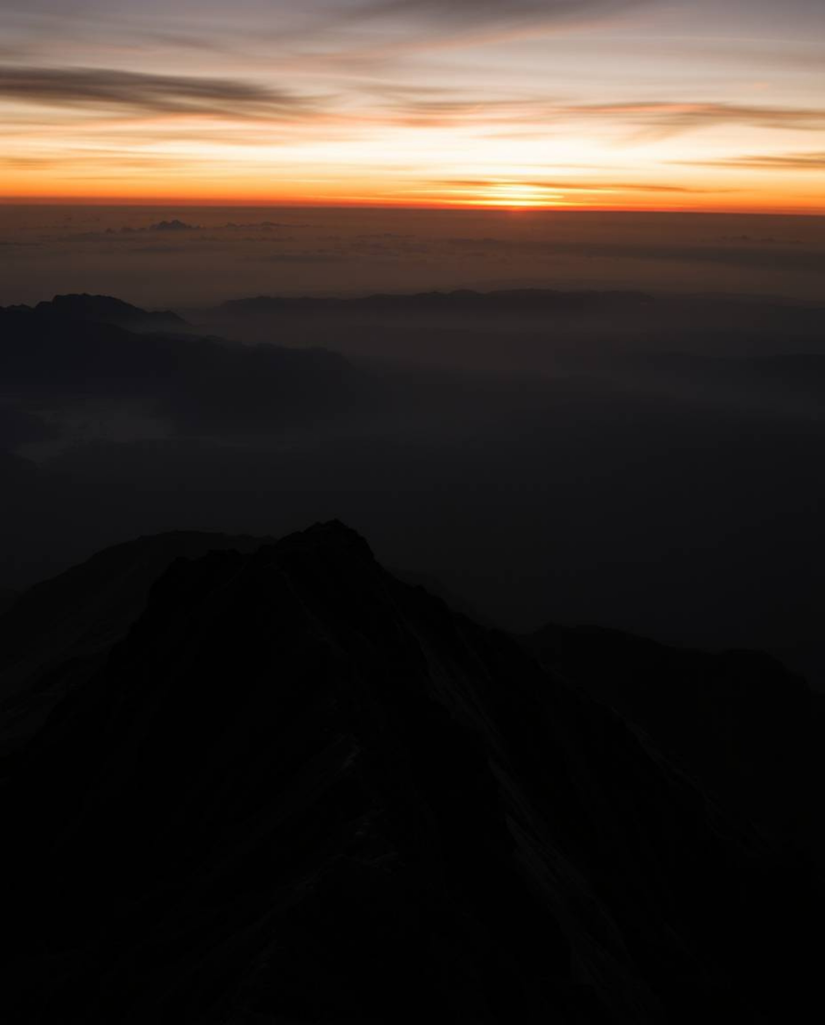 This is a stunning piece of architectural color photography capturing a sunset from a high alpine peak in intense, pure jet b