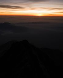 This is a stunning piece of architectural color photography capturing a sunset from a high alpine peak in intense, pure jet b
