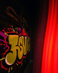 A long-exposure photograph featuring intense, dramatic lighting that highlights the colorful graffiti splashes on a weathered