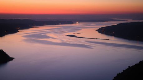 A captivating photograph of a river delta at twilight, bathed in the gentle glow of candlelight. The image showcases smooth g