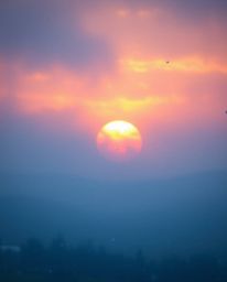 A captivating scene with a soft, dreamy atmosphere depicts snowflakes falling during a vibrant sunset. The image is bathed in