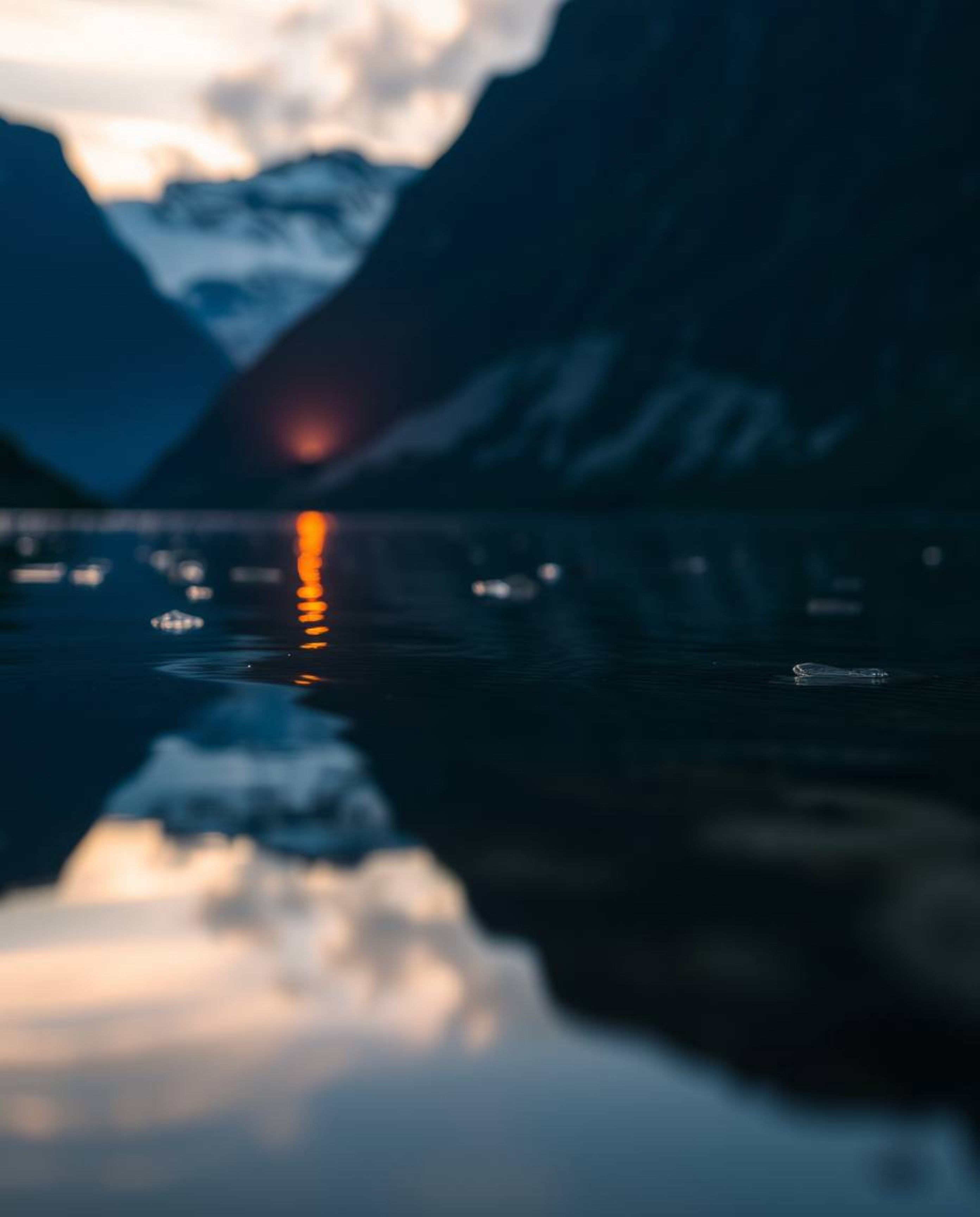 A tight close-up shot that provides a detailed focus on the reflection of a sunset in a glassy fjord, highlighting the intric