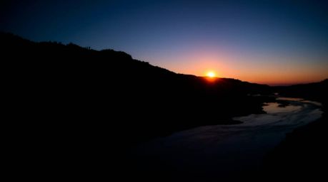 Experience the mesmerizing beauty of a silhouetted river delta bathed in the vibrant hues of twilight.  This low-angle perspe