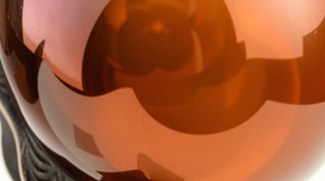 This artwork showcases a cast bronze sculpture with a captivating close-up detail of a glass object reflecting smooth gradien