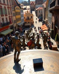 A captivating bronze sculpture depicts a vibrant musical number in a bright town square.  Viewed from an elevated position, t