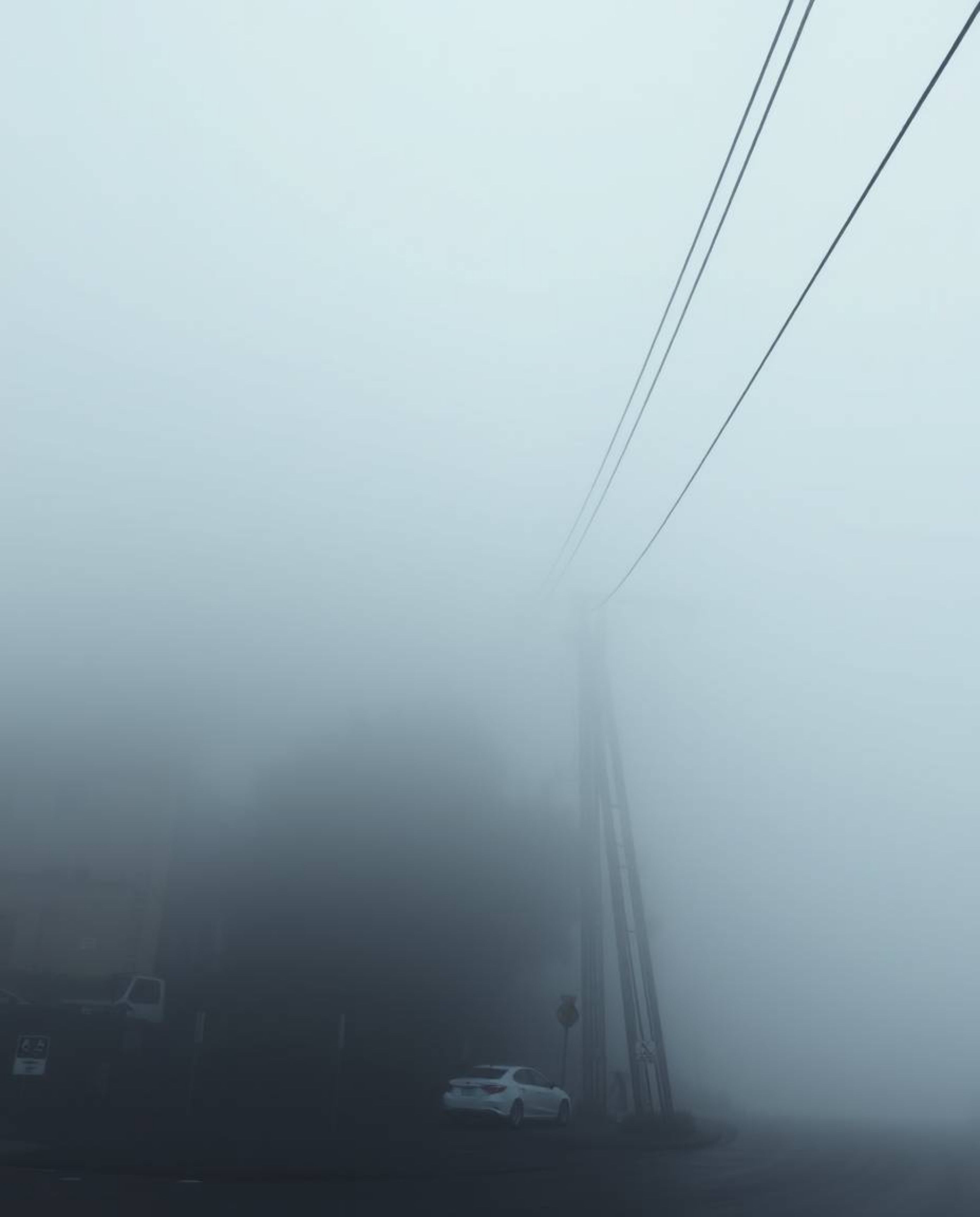 Experience a surreal street scene shrouded in fog, viewed from a high angle, where buildings appear to fold and twist in impr