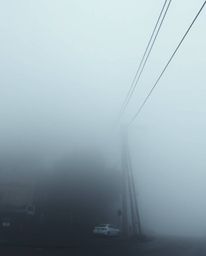Experience a surreal street scene shrouded in fog, viewed from a high angle, where buildings appear to fold and twist in impr