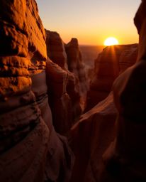 This sculptural clay art depicts a sunset illuminating sandstone cliffs in a canyon, captured from a dynamic low-angle perspe