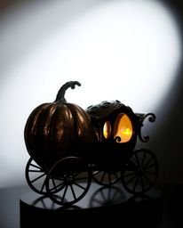 A captivating cast bronze sculpture depicts a magical pumpkin transforming into a carriage.  The chiaroscuro lighting techniq