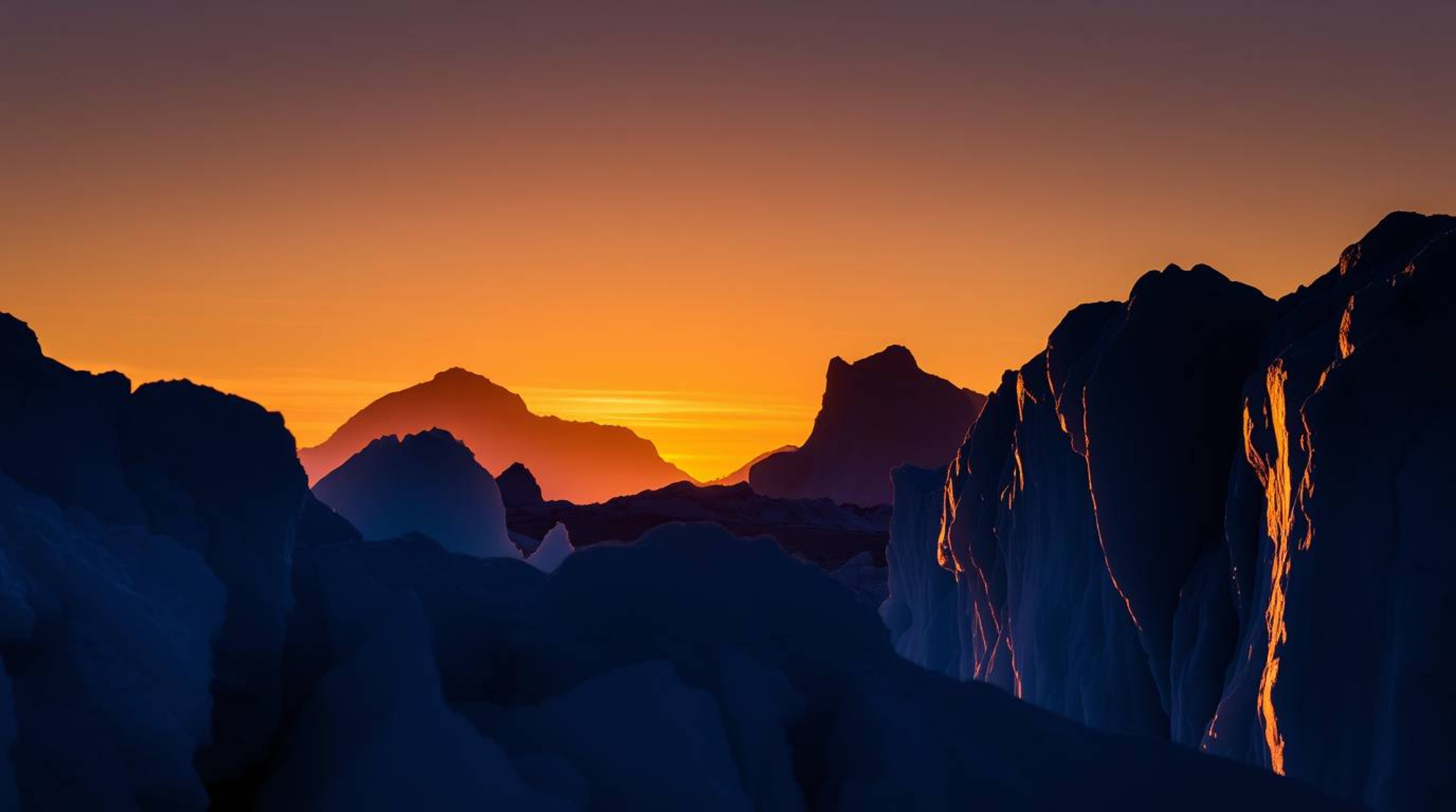 Witness the breathtaking beauty of silhouetted icy glaciers at sunset in the polar region. Backlighting creates stunning irid