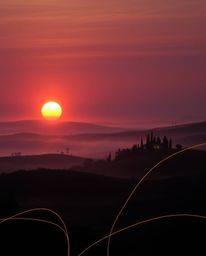 This is a creative light art piece depicting a sunset over the misty, rolling hills of Tuscany. The artwork employs artistic 