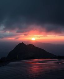 This artwork captures a sunset from a high alpine peak in a strong, moody style. It depicts a wet, rainy scene with drizzling