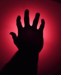 A captivating image featuring a silhouetted hand reaching towards a light source, rendered in surreal infrared tones. The bac