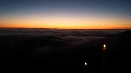 A captivating long-exposure photograph depicts fog-shrouded hills bathed in the warm glow of a setting sun.  Candlelight flic
