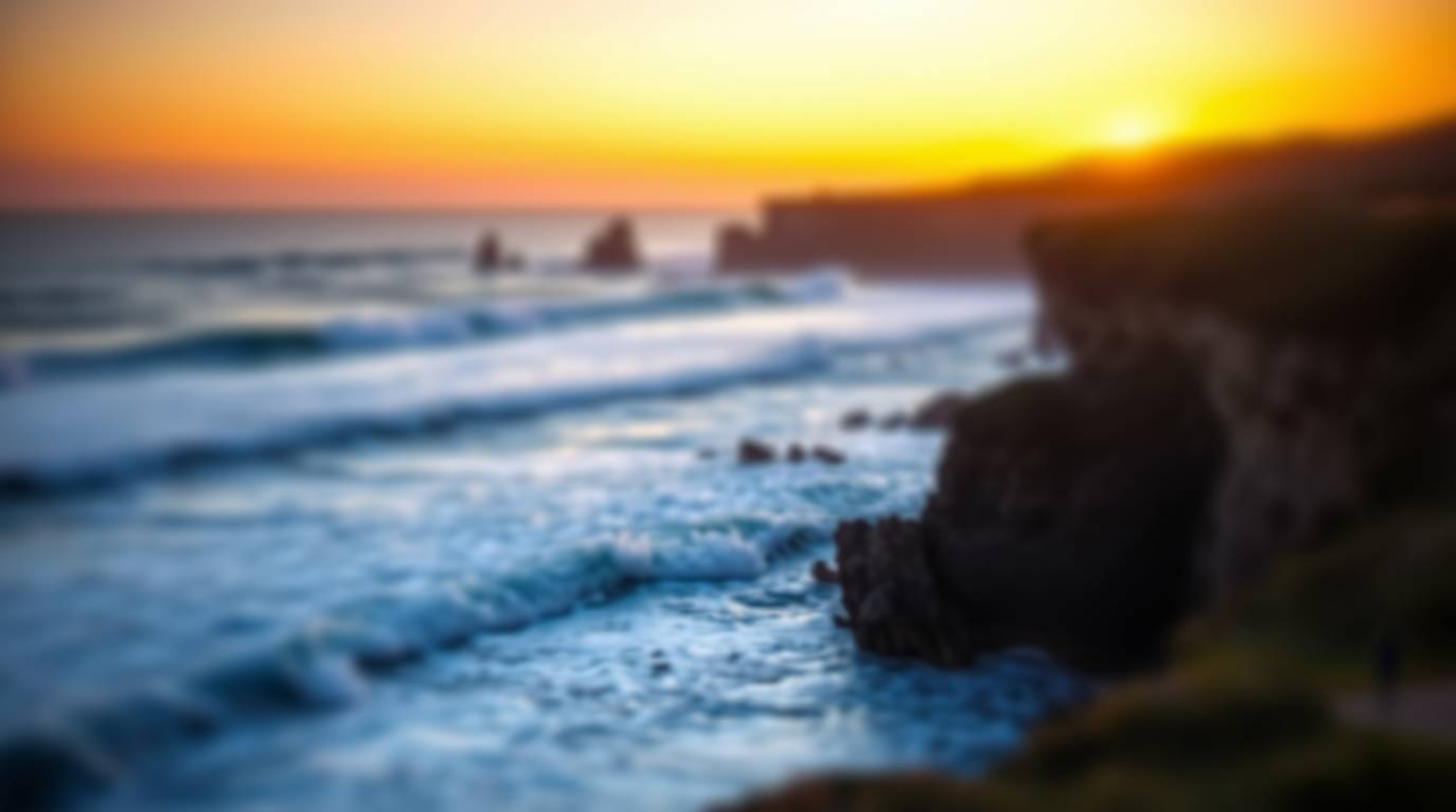 Experience the tranquility of waves crashing on majestic cliffs beneath a breathtaking sunset, captured with a captivating bl