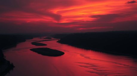 This stunning image captures a winding river illuminated by a vibrant orange-pink sky, creating a dramatic and captivating sc