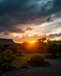 A photograph of a serene Zen garden at sunset with a blurred bokeh effect, intense dramatic weather, stormy skies, and high t