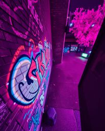 This image captures a high-angle view of a brick wall adorned with vibrant, colorful infrared graffiti, showcasing a captivat