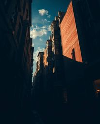 Explore a dramatic surreal street scene featuring folding and twisting buildings bathed in contrasting chiaroscuro lighting. 