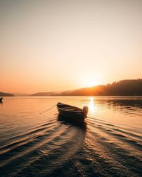 This is a photograph depicting a boat drifting on a lake during the golden hour. The scene is bathed in warm, natural earth t