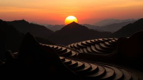 This captivating sculptural clay art piece depicts a mesmerizing silhouetted sunset over lush rice terraces nestled in the mo