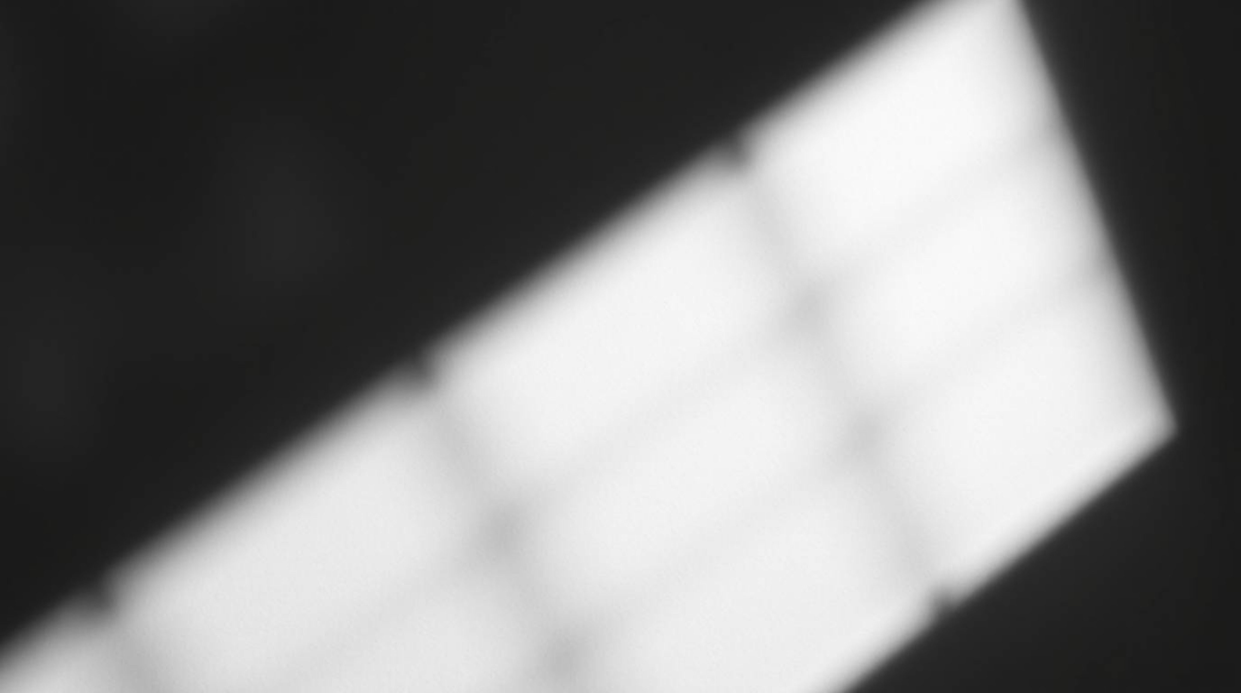 This abstract composition features a high contrast, low-key lighting scheme casting deep shadows across an abstract gradient