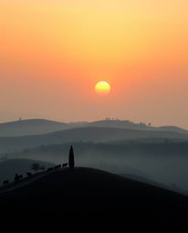 This is a strong, moody style image depicting a sunset over misty rolling hills in Tuscany, realized as sculptural clay art. 