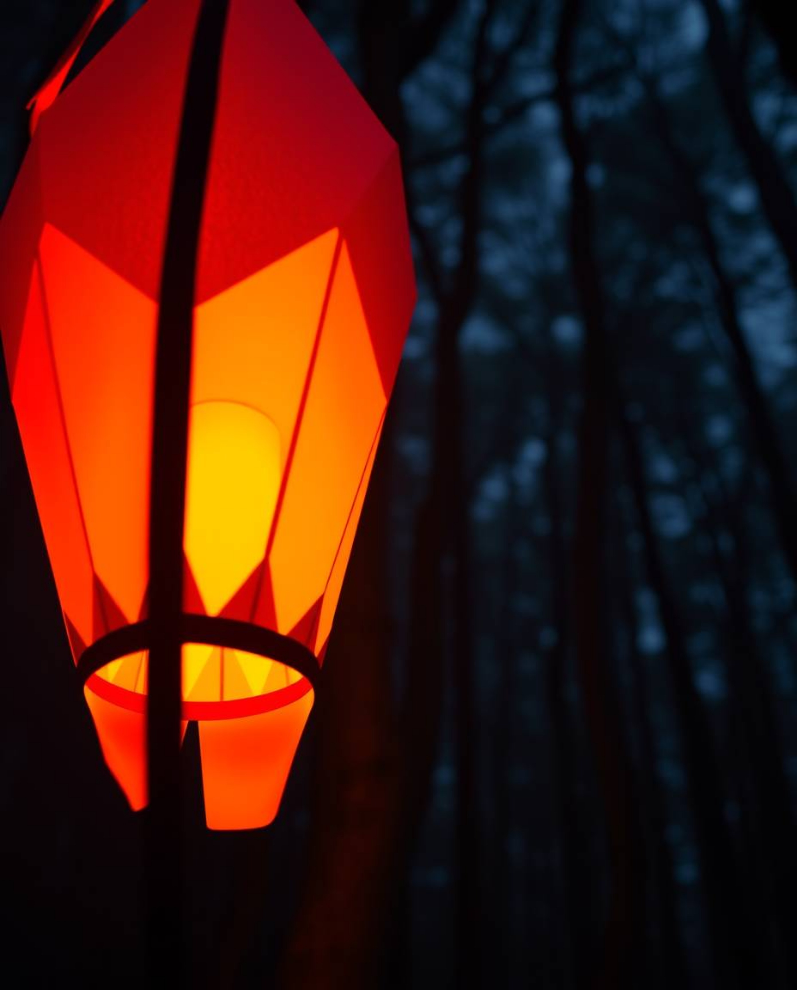 Discover a captivating image of a glowing origami lantern nestled within a dark forest.  The intricate, geometrically precise