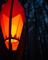 Discover a captivating image of a glowing origami lantern nestled within a dark forest.  The intricate, geometrically precise